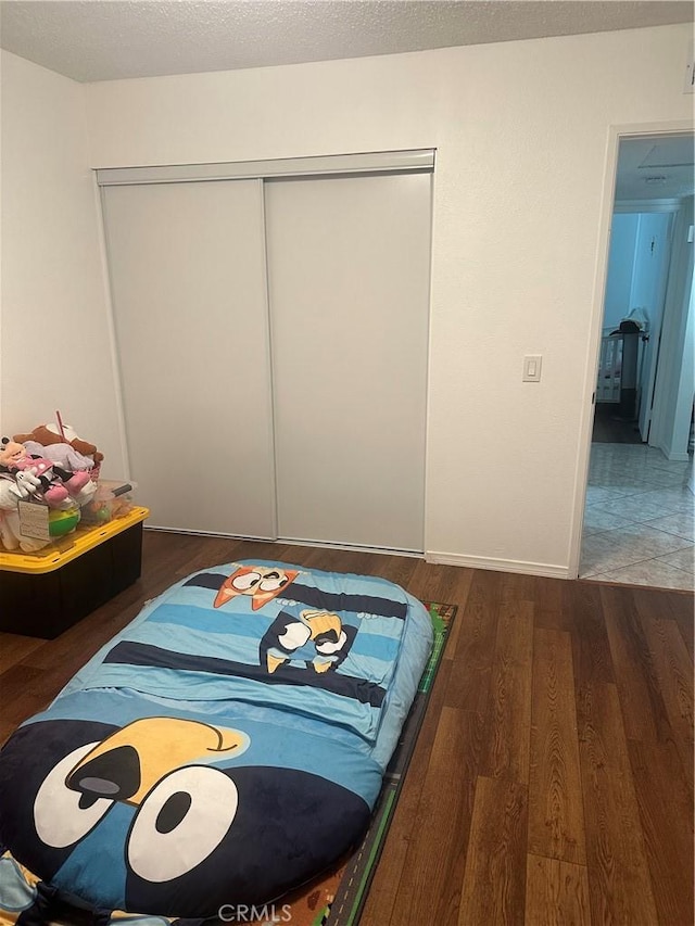 bedroom with a textured ceiling, dark hardwood / wood-style flooring, and a closet