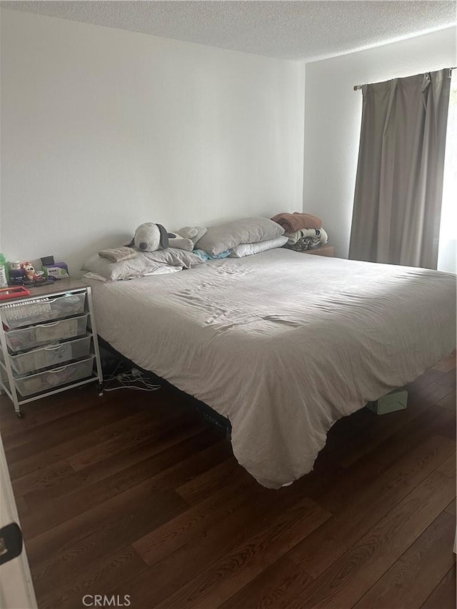 bedroom with dark wood-type flooring and a textured ceiling