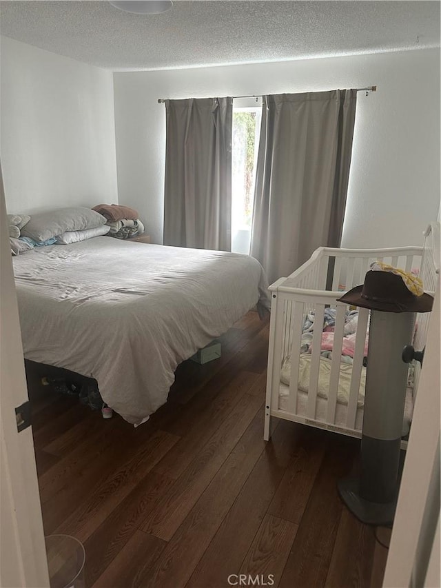 bedroom with dark wood-type flooring and a textured ceiling