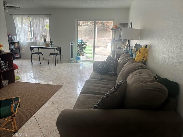 living room featuring a wealth of natural light, light tile patterned floors, ceiling fan, and a textured ceiling