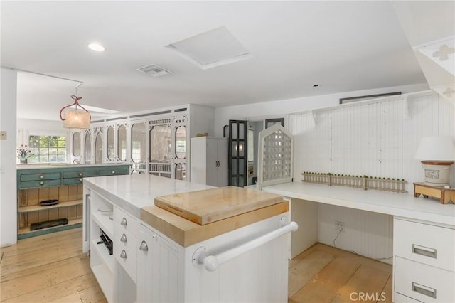 kitchen with white cabinetry, light wood-type flooring, and decorative light fixtures