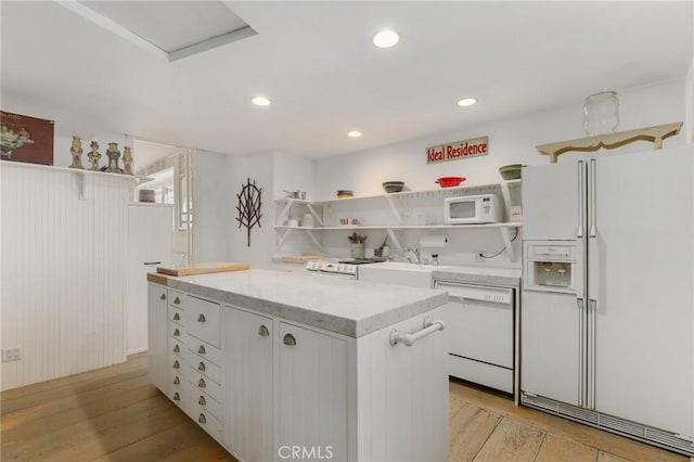 kitchen with white cabinetry, white appliances, a center island, and light hardwood / wood-style flooring