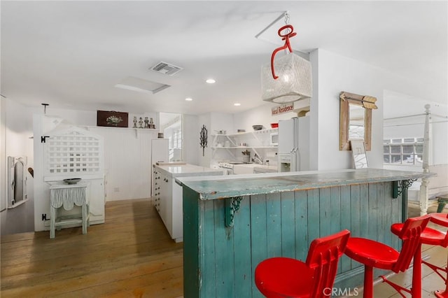 kitchen with dark hardwood / wood-style floors, white cabinets, white appliances, and kitchen peninsula