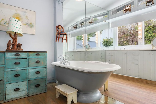 bathroom featuring wood-type flooring, a bathing tub, sink, and a wealth of natural light