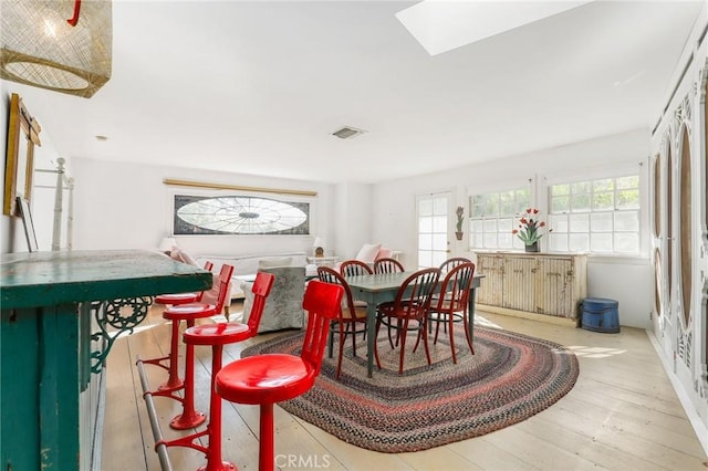 dining space with a skylight and light hardwood / wood-style flooring