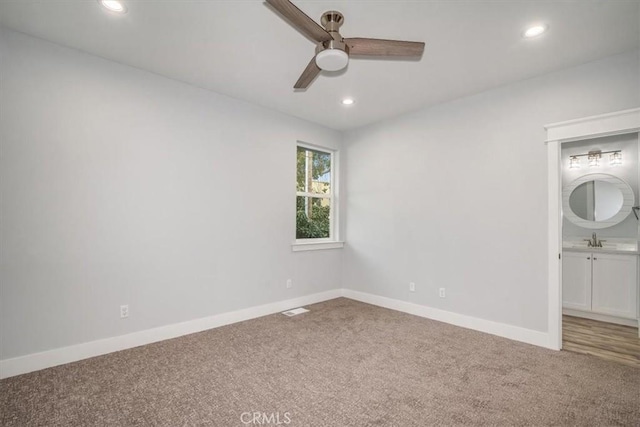 unfurnished bedroom with sink, carpet floors, ceiling fan, and ensuite bathroom