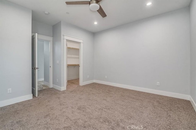 unfurnished bedroom with ceiling fan, light colored carpet, a spacious closet, and a closet