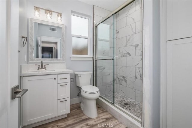 bathroom with vanity, wood-type flooring, a shower with door, and toilet