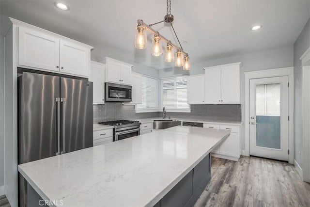 kitchen featuring pendant lighting, sink, white cabinets, and appliances with stainless steel finishes