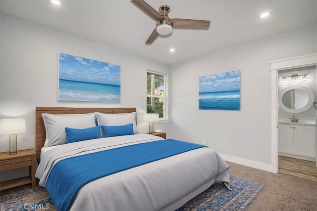 bedroom with ceiling fan, ensuite bathroom, carpet flooring, and sink