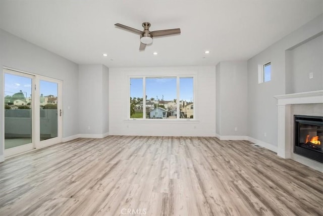 unfurnished living room with ceiling fan, a healthy amount of sunlight, and light wood-type flooring