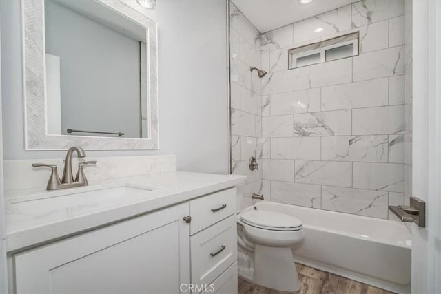 full bathroom featuring vanity, tiled shower / bath combo, wood-type flooring, and toilet