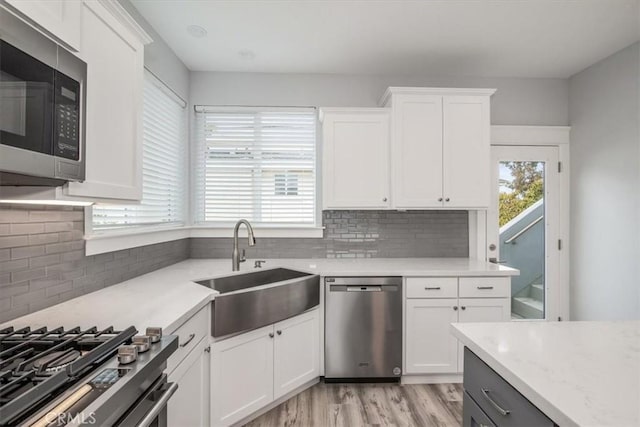 kitchen with stainless steel appliances, a wealth of natural light, sink, and white cabinets