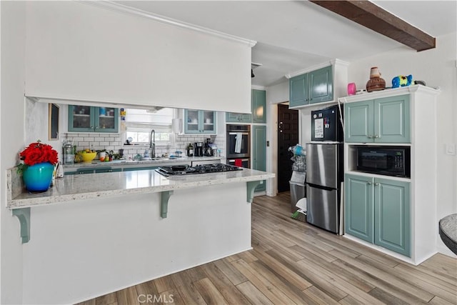 kitchen with tasteful backsplash, sink, light hardwood / wood-style floors, kitchen peninsula, and stainless steel appliances