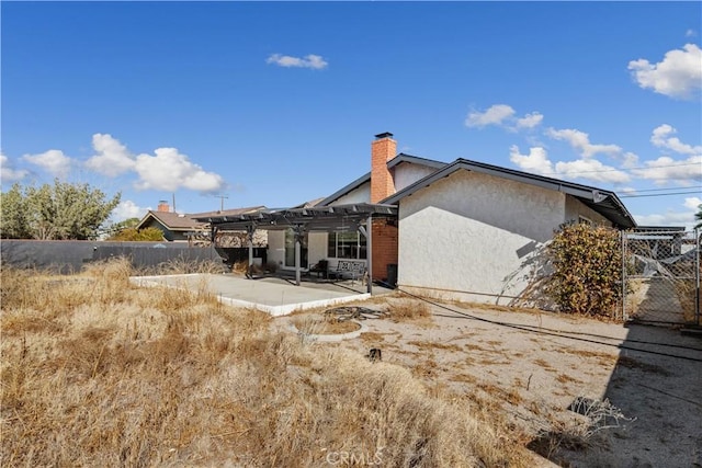 rear view of property featuring a pergola and a patio