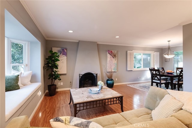 living room with ornamental molding, a large fireplace, and light hardwood / wood-style flooring