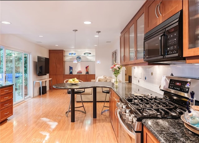 kitchen featuring pendant lighting, dark stone countertops, light hardwood / wood-style floors, gas stove, and decorative backsplash