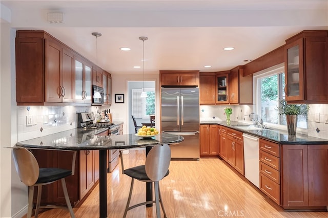 kitchen with appliances with stainless steel finishes, pendant lighting, sink, a kitchen breakfast bar, and kitchen peninsula