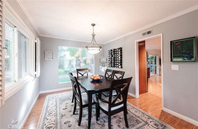 dining room with crown molding and light hardwood / wood-style flooring