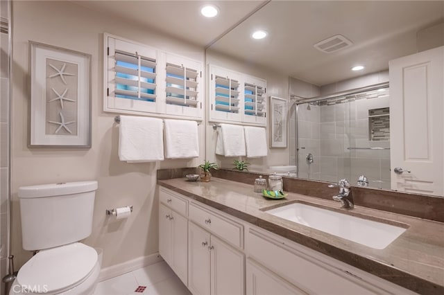 bathroom with a shower with door, vanity, tile patterned flooring, and toilet