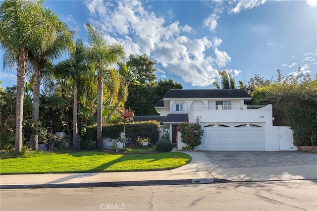 view of front property with a garage, a front yard, and a balcony