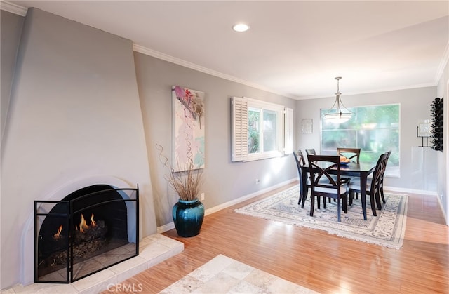 dining room featuring hardwood / wood-style flooring, crown molding, and a tile fireplace