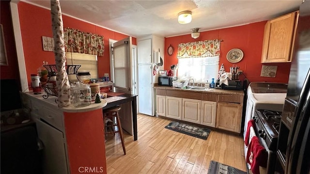 kitchen featuring light hardwood / wood-style flooring, sink, gas range, and a breakfast bar area