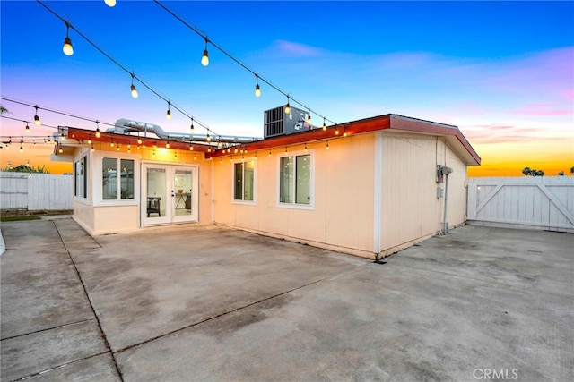 back house at dusk featuring central AC, a patio, and french doors