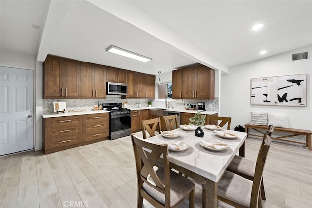 kitchen featuring tasteful backsplash, appliances with stainless steel finishes, and light wood-type flooring