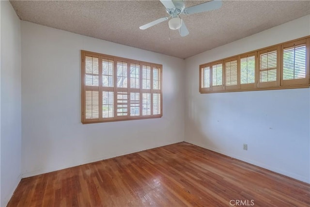 spare room with hardwood / wood-style floors, a textured ceiling, and a wealth of natural light