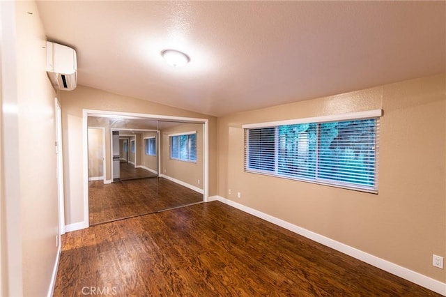 23821 Hillhurst Dr W Unit 44, Laguna Niguel, CA 92677 - empty room featuring a wall mounted AC, wood finished floors, vaulted ceiling, and baseboards
