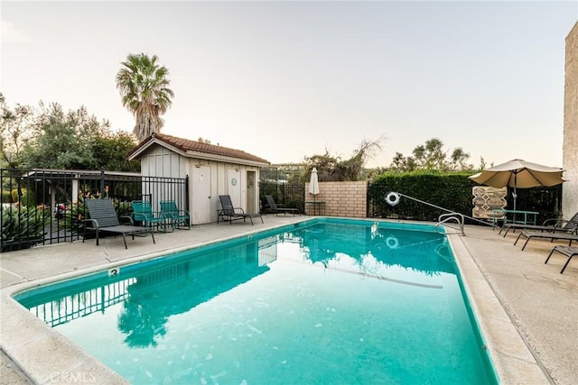 pool featuring fence, an outdoor structure, and a patio area