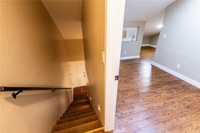 staircase with baseboards, a textured wall, and wood finished floors