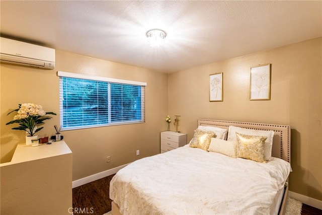 bedroom featuring baseboards, a wall unit AC, and dark wood finished floors