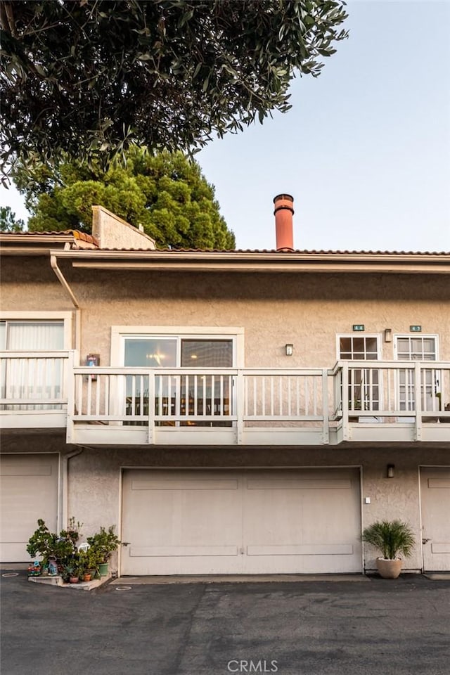 rear view of property featuring a garage and a balcony