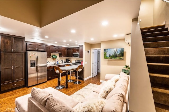 living room featuring sink, light hardwood / wood-style flooring, and a wall mounted AC