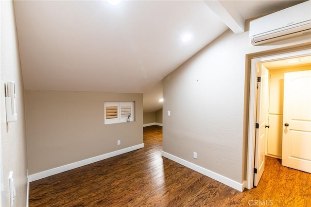 unfurnished room with baseboards, lofted ceiling with beams, an AC wall unit, and wood finished floors