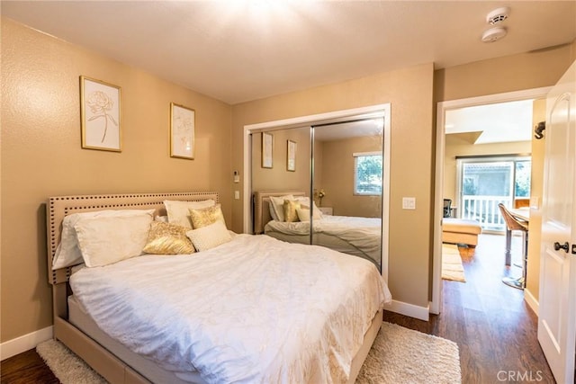 bedroom featuring dark wood-type flooring, baseboards, and a closet