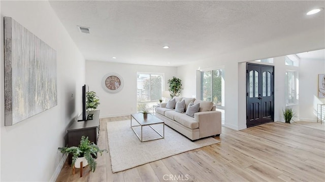 living room with a textured ceiling and light hardwood / wood-style flooring