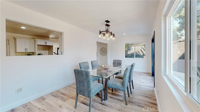 dining area with light hardwood / wood-style flooring and a notable chandelier