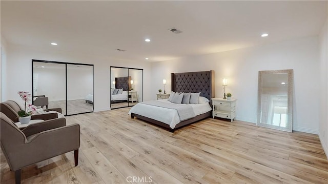 bedroom featuring two closets and light hardwood / wood-style flooring