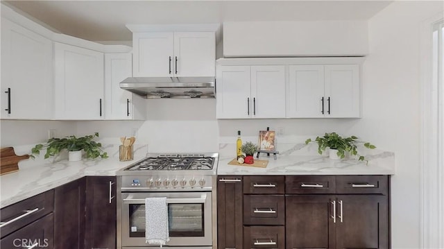 kitchen featuring light stone counters, dark brown cabinets, high end stove, and white cabinets