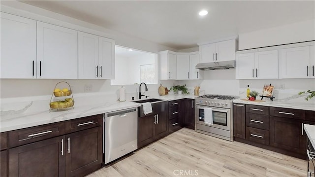 kitchen featuring sink, stainless steel appliances, light stone countertops, white cabinets, and light wood-type flooring