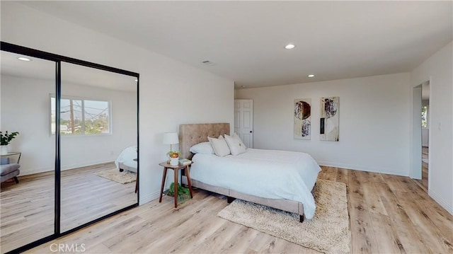 bedroom with light hardwood / wood-style floors and a closet