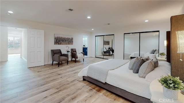 bedroom featuring multiple closets and light hardwood / wood-style floors