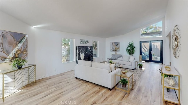 living room with a healthy amount of sunlight, light wood-type flooring, and french doors