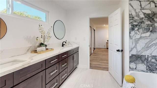 bathroom with vanity, a tub, and wood-type flooring