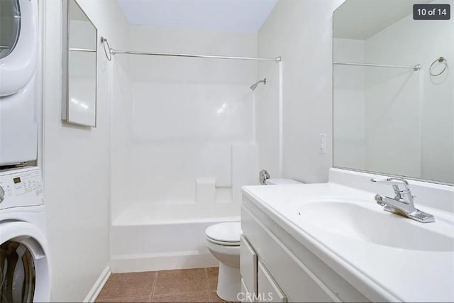 full bathroom featuring shower / tub combination, stacked washer and dryer, vanity, toilet, and tile patterned floors