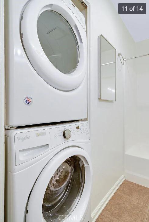 laundry area with light tile patterned flooring and stacked washer and dryer