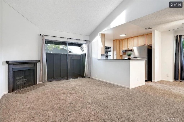 unfurnished living room featuring light carpet, a fireplace, a textured ceiling, and vaulted ceiling